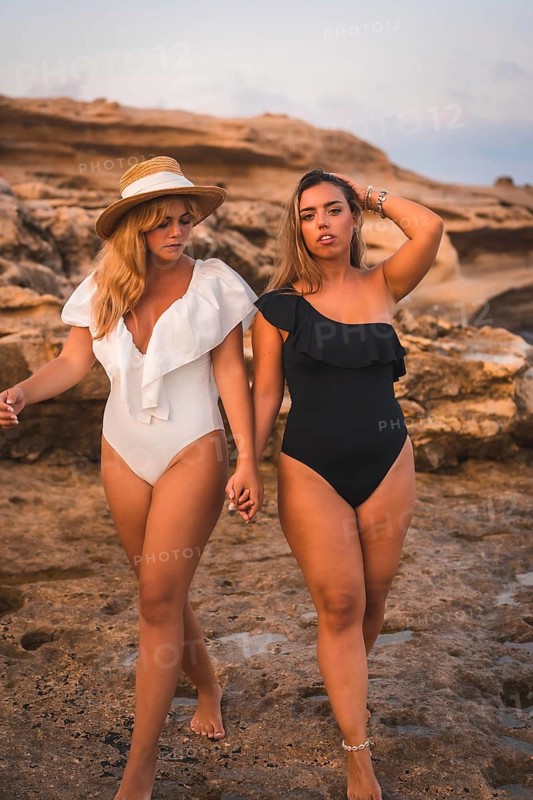 Lifestyle of a couple of Caucasian lesbian girls walking on the beach. Black and white bathroom contractions