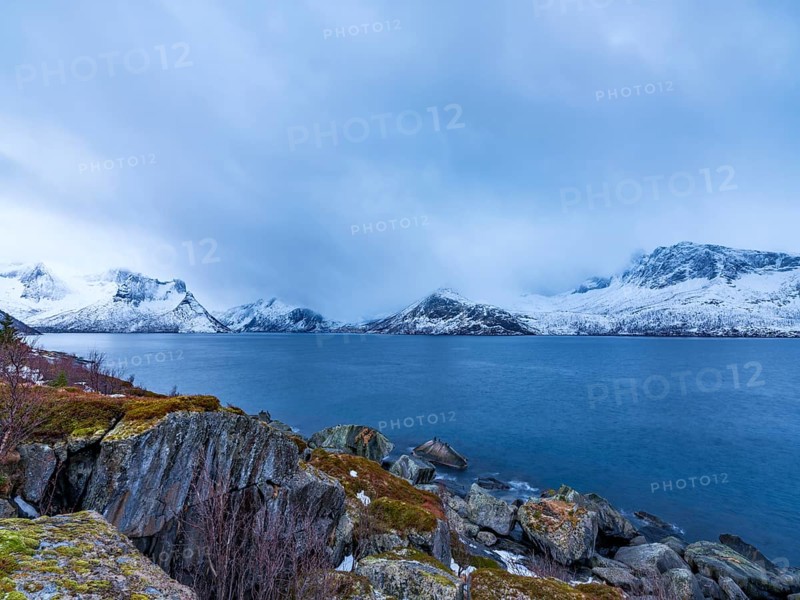 View across the fjord to snowy mountains, Husøy, Senja island, Troms, Norway
