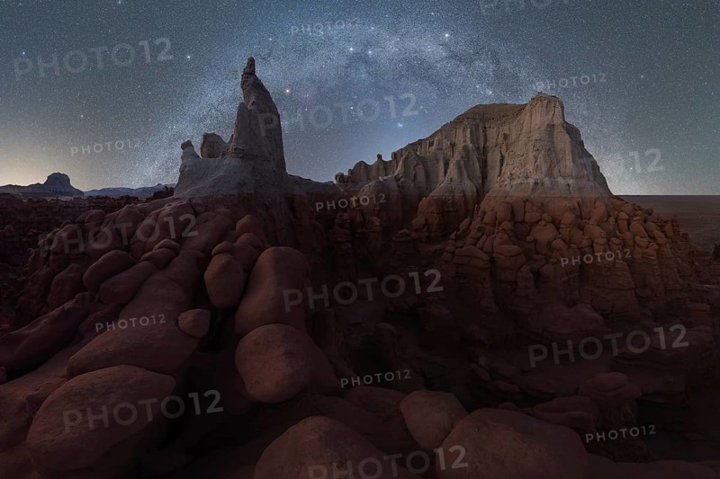 A mesmerizing view of Goblin Valley State Park under a starry sky. The unique sandstone formations are bathed in moonlight, creating an ethereal and otherworldly atmosphere