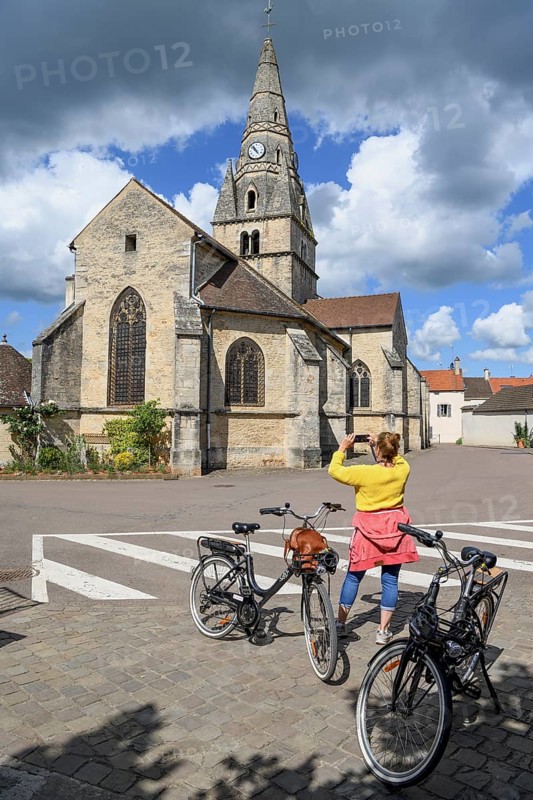 Cyclist taking photos in front of the church Église Saint-Cassien, Savigny-lès-Beaune, Département Côte-d'Or, Burgundy, France