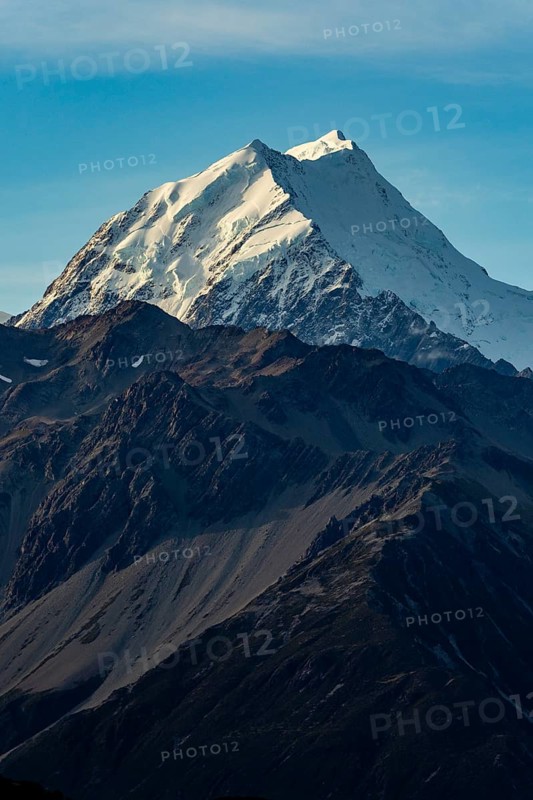 Stunning autumn view of Mount Cook, New Zealand, showcasing its snow capped peak under a clear blue sky. The rugged terrain adds dramatic beauty to the breathtaking scenery