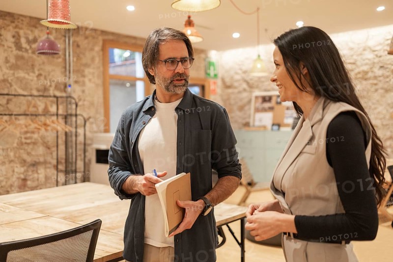 Two professionals engage in a friendly discussion in a modern coworking space The setting is vibrant and collaborative, promoting creativity and teamwork