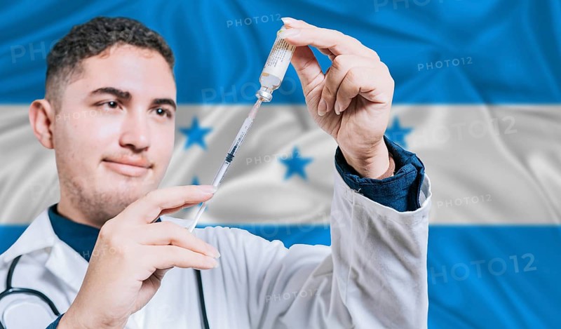Doctor holding syringe on Honduras flag background. Medical professional holding syringe with Honduran flag in the background