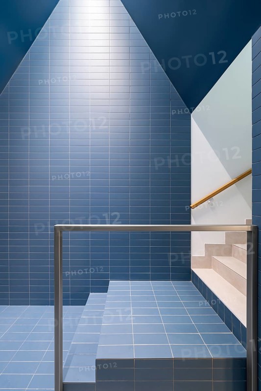 Featuring a modern interior with vibrant blue tiles, this image highlights sustainable architectural design, incorporating elements of a passive house with low-emission materials and energy-efficient structures