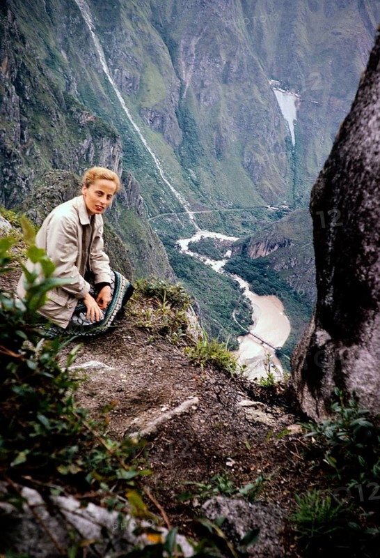 Female tourist sitting on the mountain Huayna Picchu overlooking a river gorge, Peru, South America around 1962 Urubamba River or Vilcamayo River, upstream called Vilcanota River