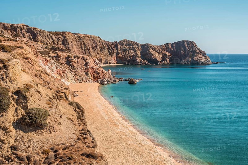 Discover Paleochori Beach on Milos Island, Greece, with its golden sands and crystal-clear turquoise waters, framed by rugged cliffs under a vivid blue sky