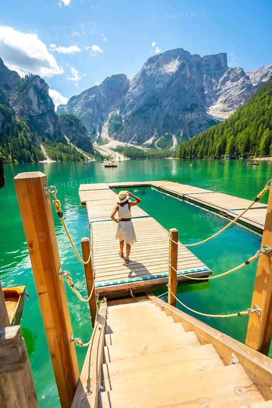 Tourist enjoying breathtaking view of lake braies in the italian dolomites, standing on a wooden pier with emerald waters and majestic mountains