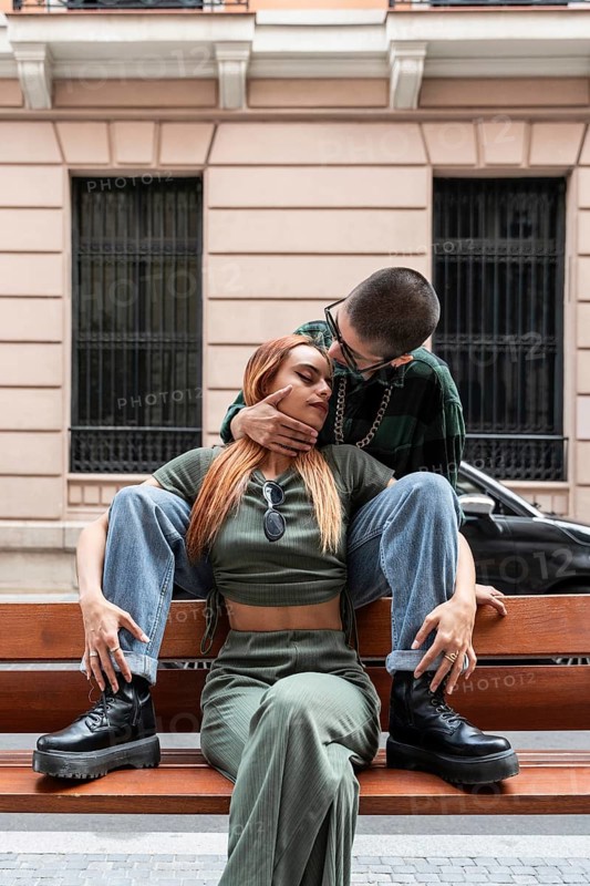 A Colombian lesbian couple sits closely on a bench outdoors, radiating love and acceptance. Their affectionate posture highlights themes of LGBTQIA+ pride and diversity
