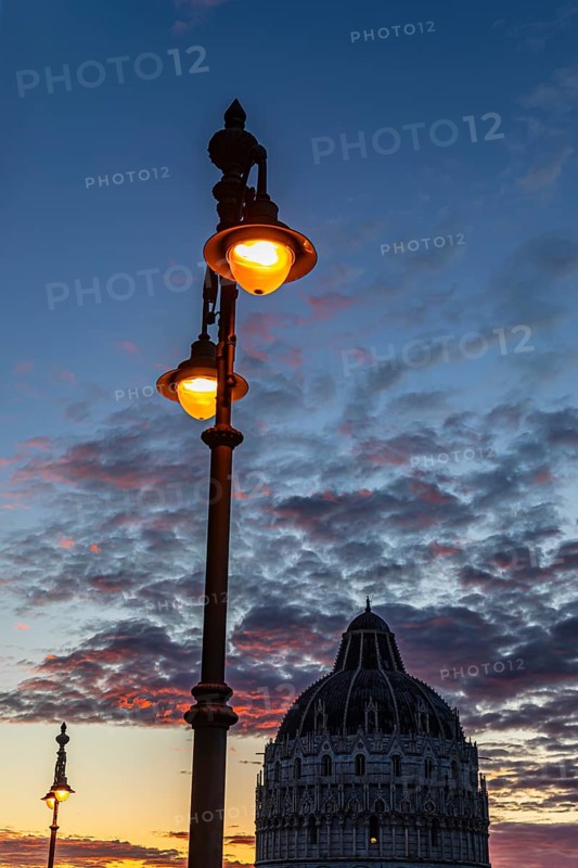 Baptistery Baptistery in the evening light under an illuminated street lamp at sunset, Pisa Tuscany, Italy