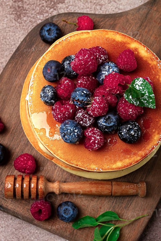 Breakfast, pancakes with berries and honey, top view, homemade, no people, on a wooden background