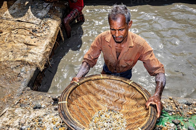 Man focuses on working in a pool of water with a filled basket, the sapphire and gemstone mines at Ratnapura in Sri Lanka