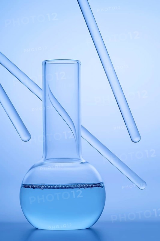 Close-up of a laboratory beaker filled with blue liquid, surrounded by transparent glass rods against a soft blue background, representing scientific experimentation