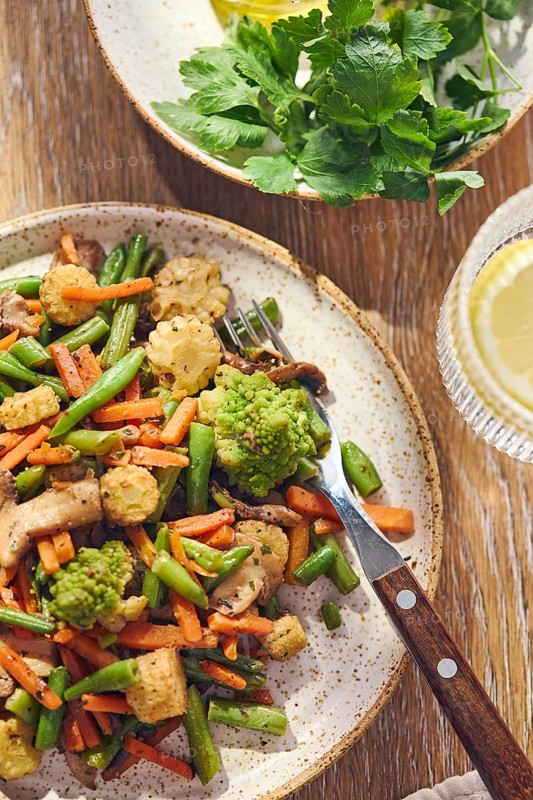 Plate of stir-fried mixed vegetables with green beans, carrots, baby corn, romanesco and mushrooms