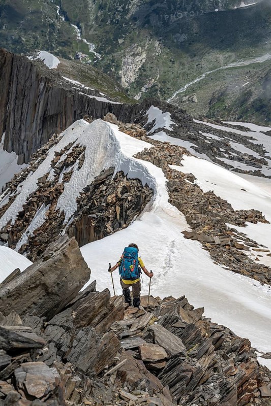 Mountaineer on a rocky ridge with snow, descent from the summit of the Schönbichler Horn, Berliner Höhenweg, Zillertal Alps, Tyrol, Austria