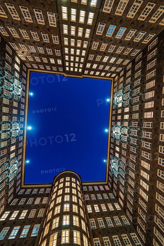 Triangular office building at night, illuminated, with street in the foreground and deep blue sky, Hamburg, Germany