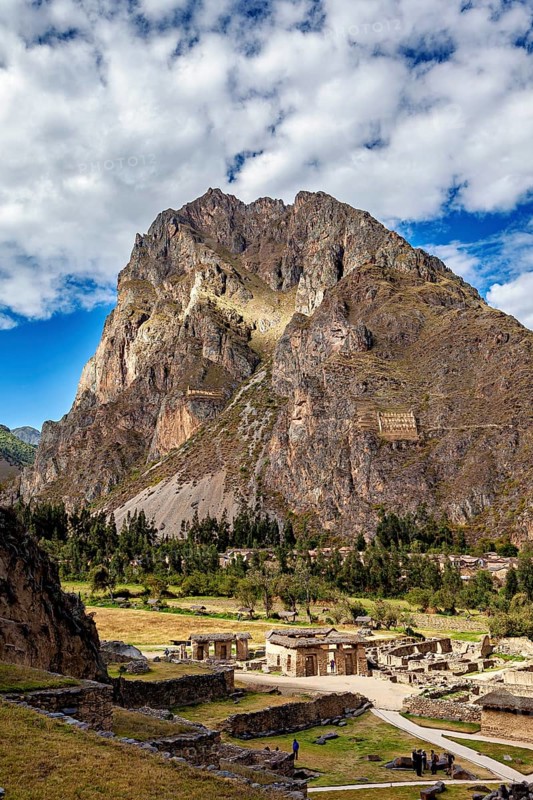 Large mountain with ruins in the foreground, clouds and sun mingle, The Inca ruins of Ollantaytambo in the Andes of Peru