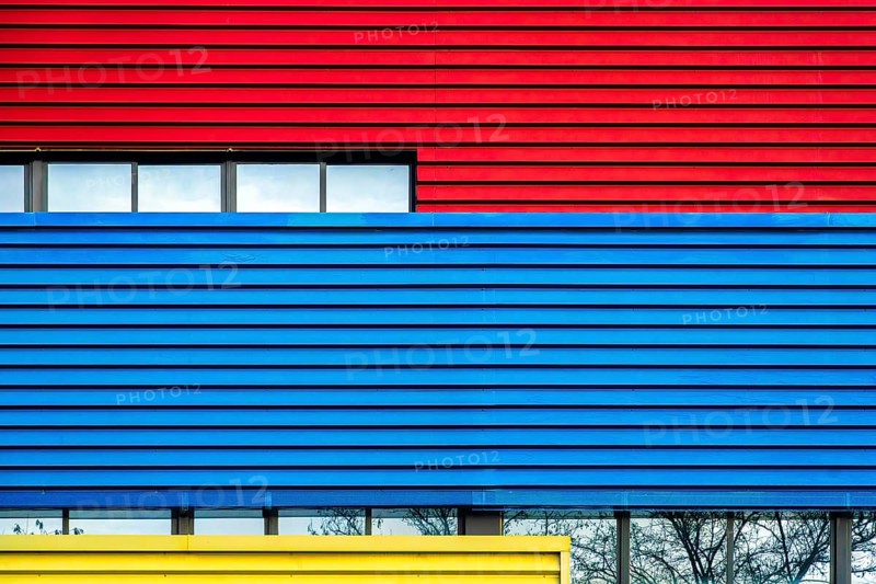 A striking image showcasing the facades of a colorful urban building in vivid red, blue, and yellow, representing modern architectural color use in city environments