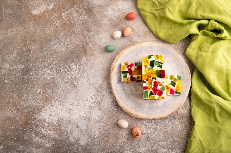 Colored Fruit and milk jelly on brown concrete background and green linen textile, top view, flat lay, copy space, minimalism
