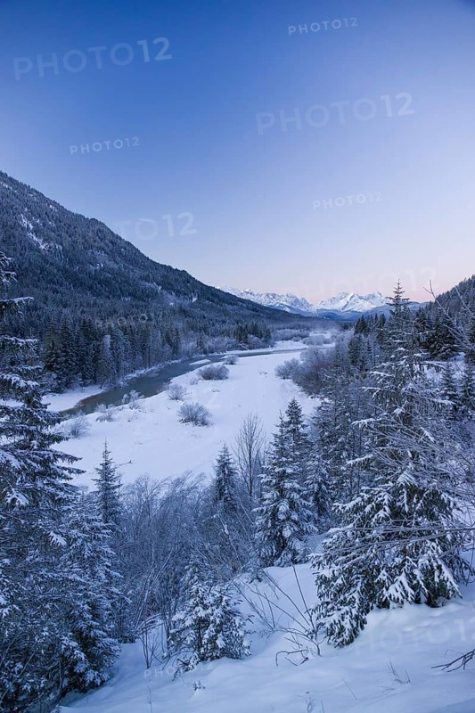 Isar valley in winter at temperatures of minus 18 degrees Celsius. Snow covered landscape with the Isar river flowing through. Some hoar frosted trees. Early morning