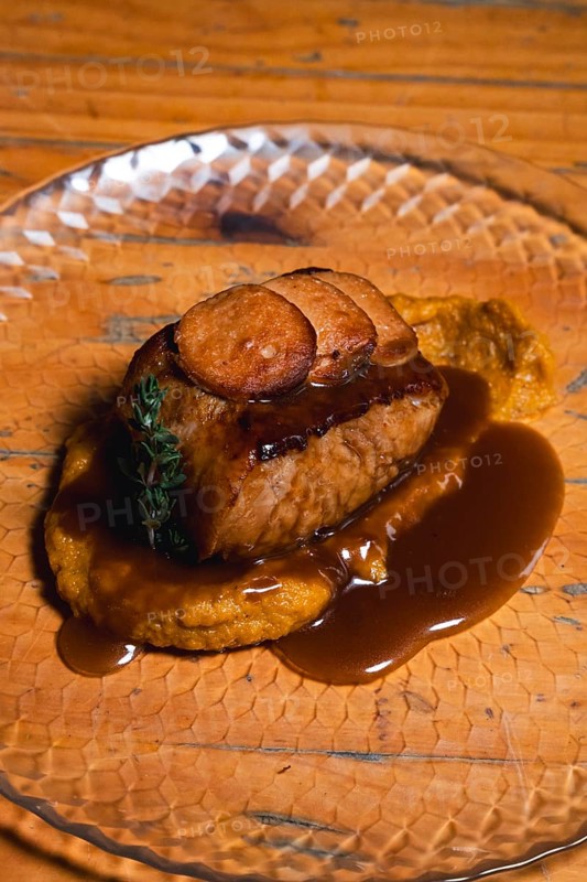 Indulge in a perfectly cooked beef tenderloin atop creamy mashed potatoes, drizzled with a flavorful sauce that elevates the dish to a new level of culinary delight