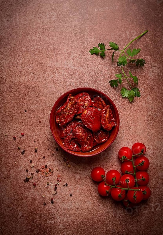 Dried tomatoes, in a bowl, top view, on a brown background