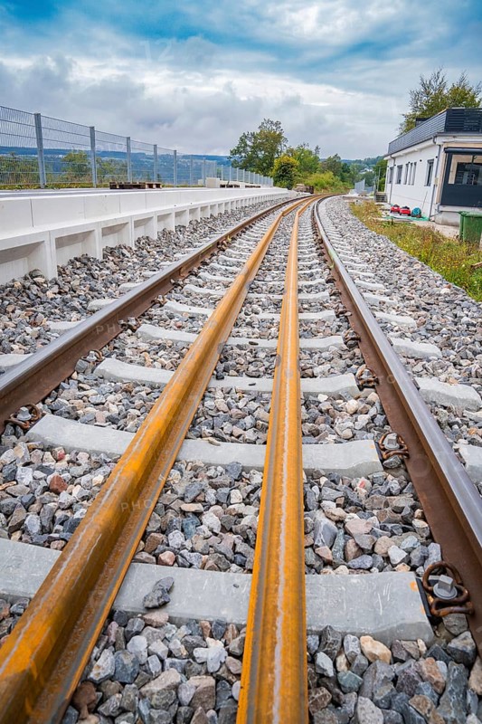 Tracks run through a landscape with buildings in the background, the atmosphere is calm and cloudy, track construction, rail delivery for Hermann Hessebahn, Calw, Black Forest, Germany