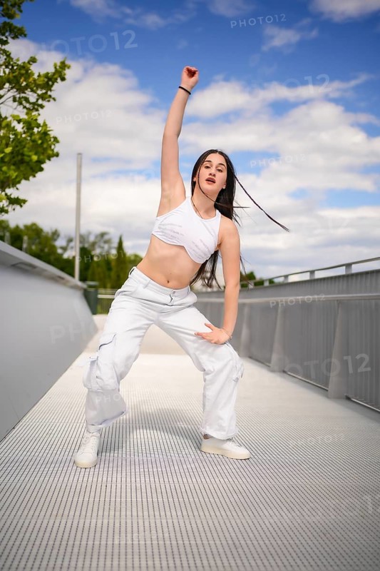 Vertical photo of a caucasian yung urban woman performing dancehall on an outdoor bridge