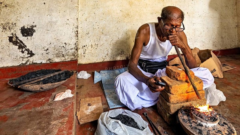 A man focuses on a small fire in a workshop, hissing sound, a man burning safire in a small oven in the town of Ratnapura in Sri Lanka