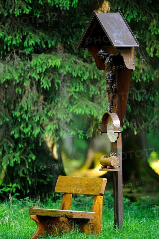 Crucifix next to a wooden bench in the forest, a place of contemplation, Bavaria