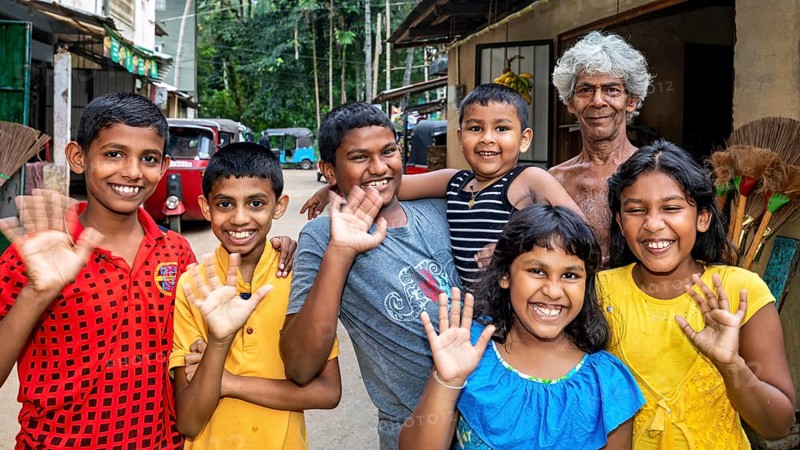 A group of children and an elderly man smiling and waving at the camera convey a sense of joy, A family in Ratnapura in Sri Lanka
