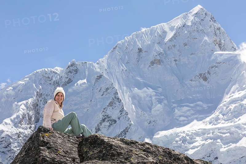 A woman enjoys an inspiring moment during her trek in the Everest region, surrounded by the towering snow-capped peaks. The breathtaking scenery exudes a sense of adventure