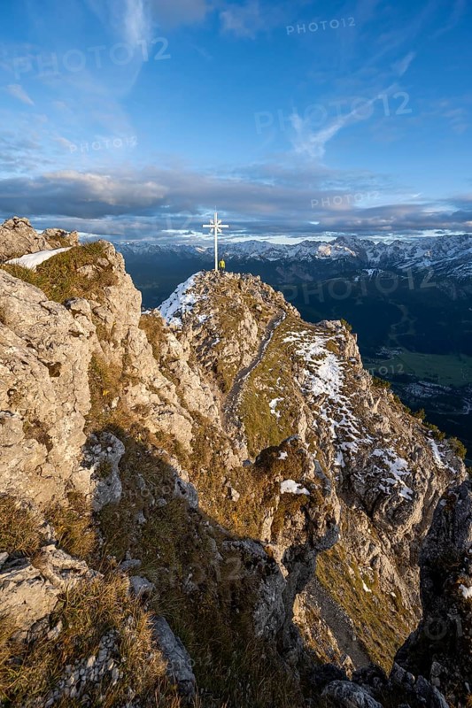 Mountaineer at the summit of the Kramerspitz with summit cross, at sunset, in autumn, Ammergau Alps, in autumn, Bavarian Alps, Bavaria, Germany