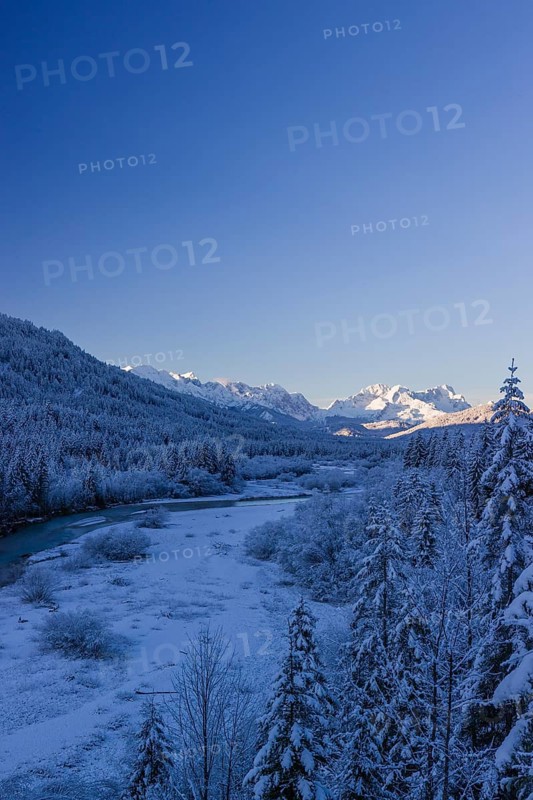 Isar valley in winter at temperatures of minus 18 degrees Celsius. Snow covered landscape with the Isar river flowing through. Some hoar frosted trees. Early morning