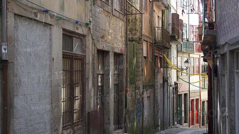 Narrow urban alley with old buildings and hanging cables in the city center, Porto, Portugal