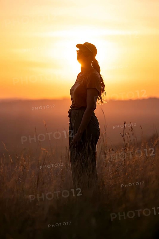 Young woman standing in tall grass at sunset, Lake Victoria, Uganda