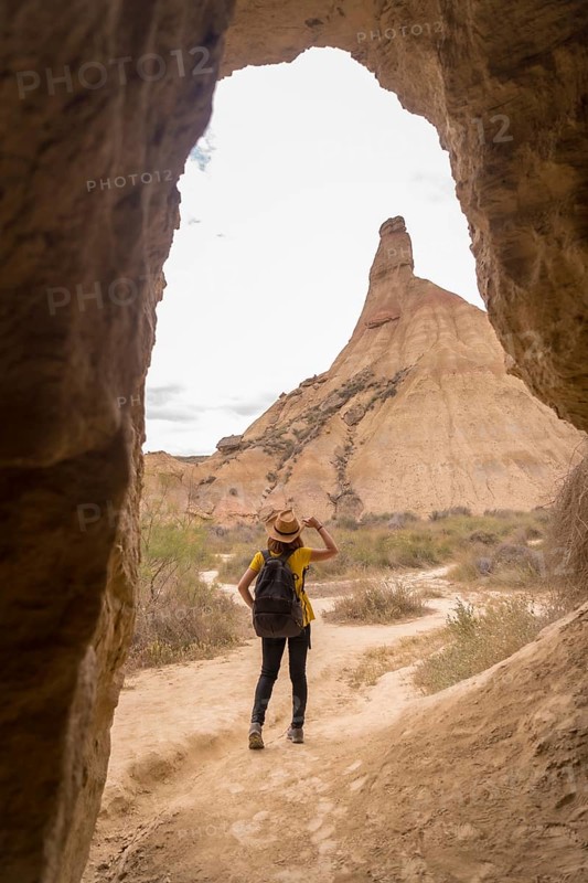 Vertical photo of a woman in summer clothes and hat walking along a path in the desert