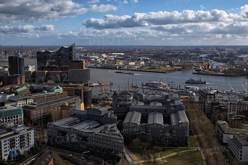 Panoramic view from the viewing platform of Hamburger Michels with river view, docks and distinctive Elbe Philharmonic Hall under cloudy sky, Hamburg, Germany