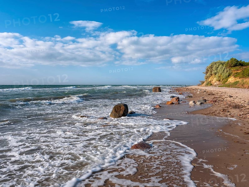 Unspoiled secluded stretch of coast with cliffs and boulders in the surf on the beach of the stormy Baltic Sea, foam crowns on the waves, near Rerik, Mecklenburg-Western Pomerania, Germany