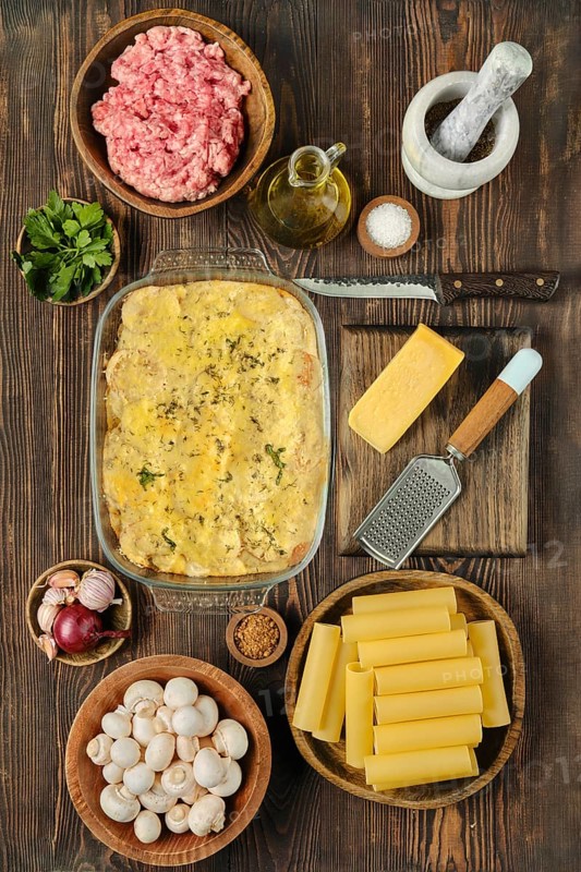Fresh ground meat, vegetables, and spices arranged around a delicious baked pasta casserole in a cozy kitchen setting