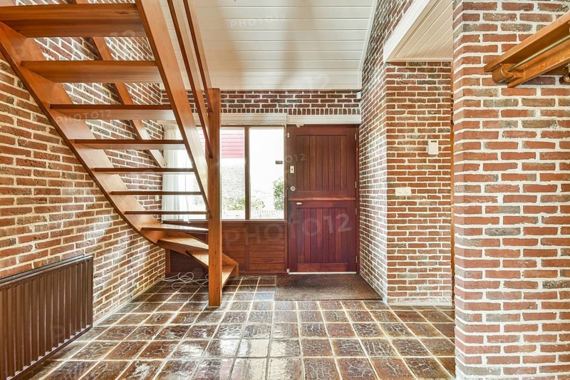 A modern interior showcasing a staircase made of wood, complemented by exposed brick walls, creating a warm and inviting atmosphere