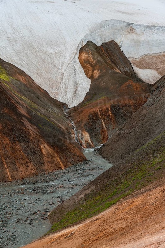 Steaming stream between colourful rhyolite mountains and snowfields, Hveradalir geothermal area, Kerlingarfjöll, Icelandic Highlands, Iceland