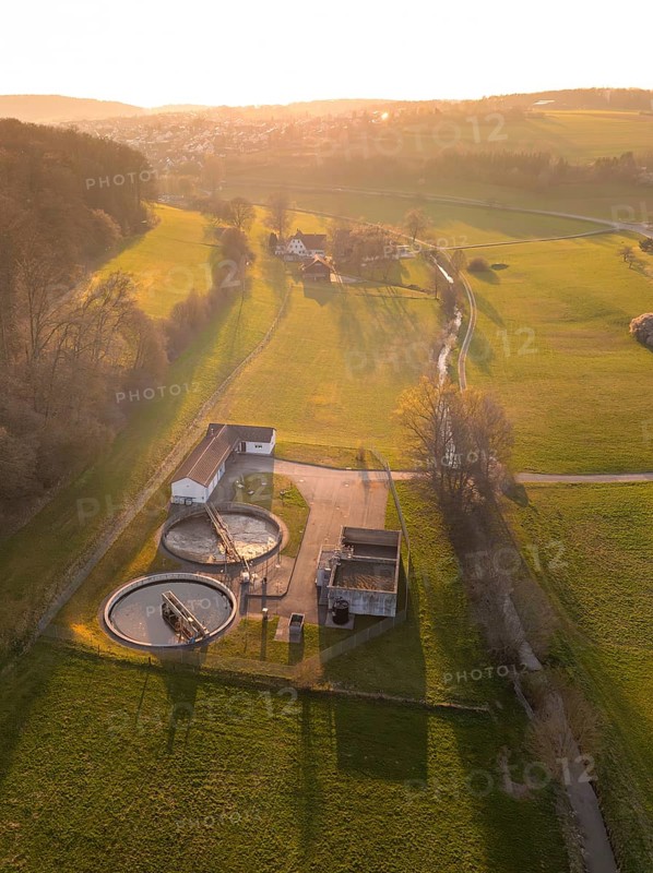 Sewage treatment plant surrounded by green fields and trees, captured at sunset in a quiet rural area, Gechingen, Calw district, Black Forest, Germany