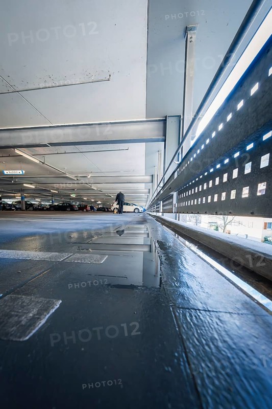 View along a multi-storey car park with concrete floor and puddle reflecting the light, Kaufland Calw multi-storey car park, Calw district, Black Forest, Germany