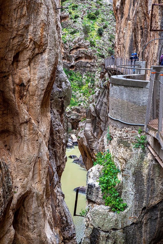 The Caminito del Rey hiking trail along steep rock faces in a picturesque gorge with green vegetation, Malaga, Spain
