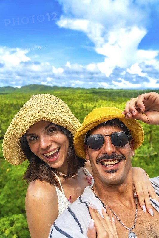 Happy couple smiling and enjoying the landscape at a coconut plantation during their holiday in siargao island, philippines