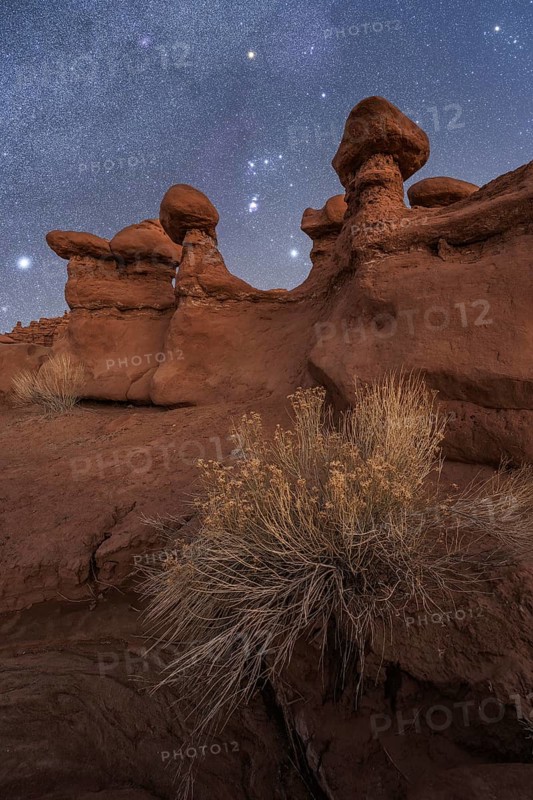 A nighttime scene in Goblin Valley State Park, Utah, featuring unique sandstone formations under a starlit sky. The natural beauty and serenity create a captivating landscape