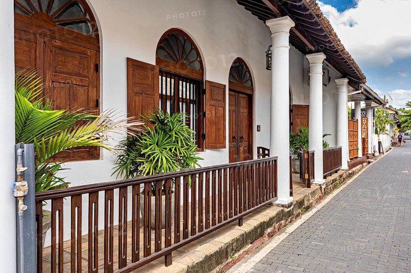 Colonial-style building decorated with wooden doors and pillars surrounded by greenery, The historic downtown of Galle in Sri Lanka
