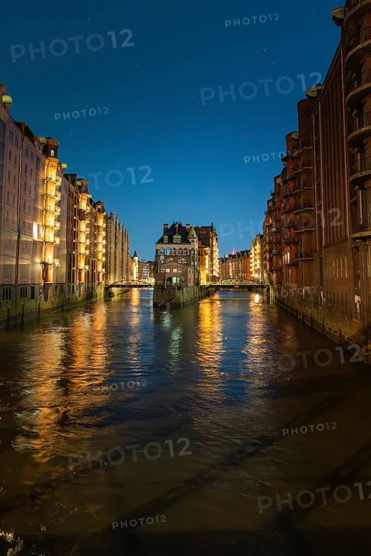 Illuminated canal buildings at night, reflected in the water, under a clear sky, Hamburg, Germany