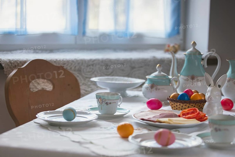 Decorated table with coffee pot, crockery, painted eggs and a porcelain bunny