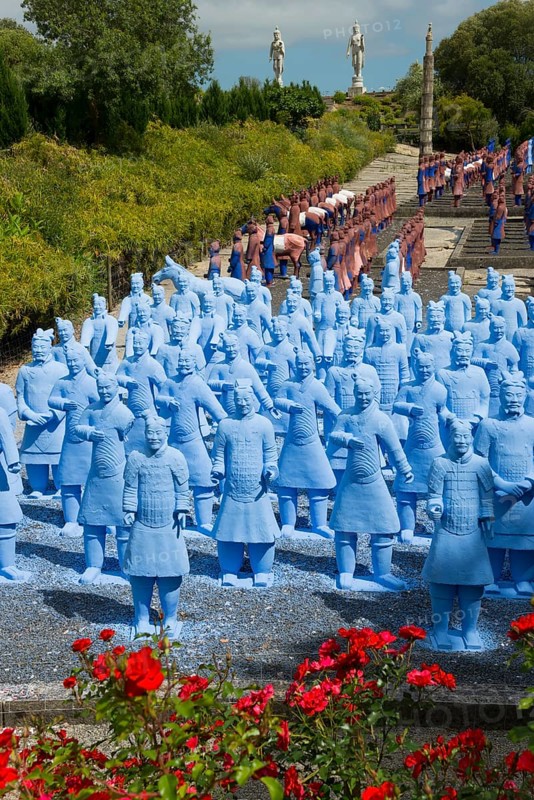 A large number of blue terracotta soldier statues stand on a path lined with flowers, Bacalhôa, Bacalhoa Buddha Eden, Quinta dos Loridos, largest oriental garden in Europe, Bombarral, Oeste, Centro, Portugal